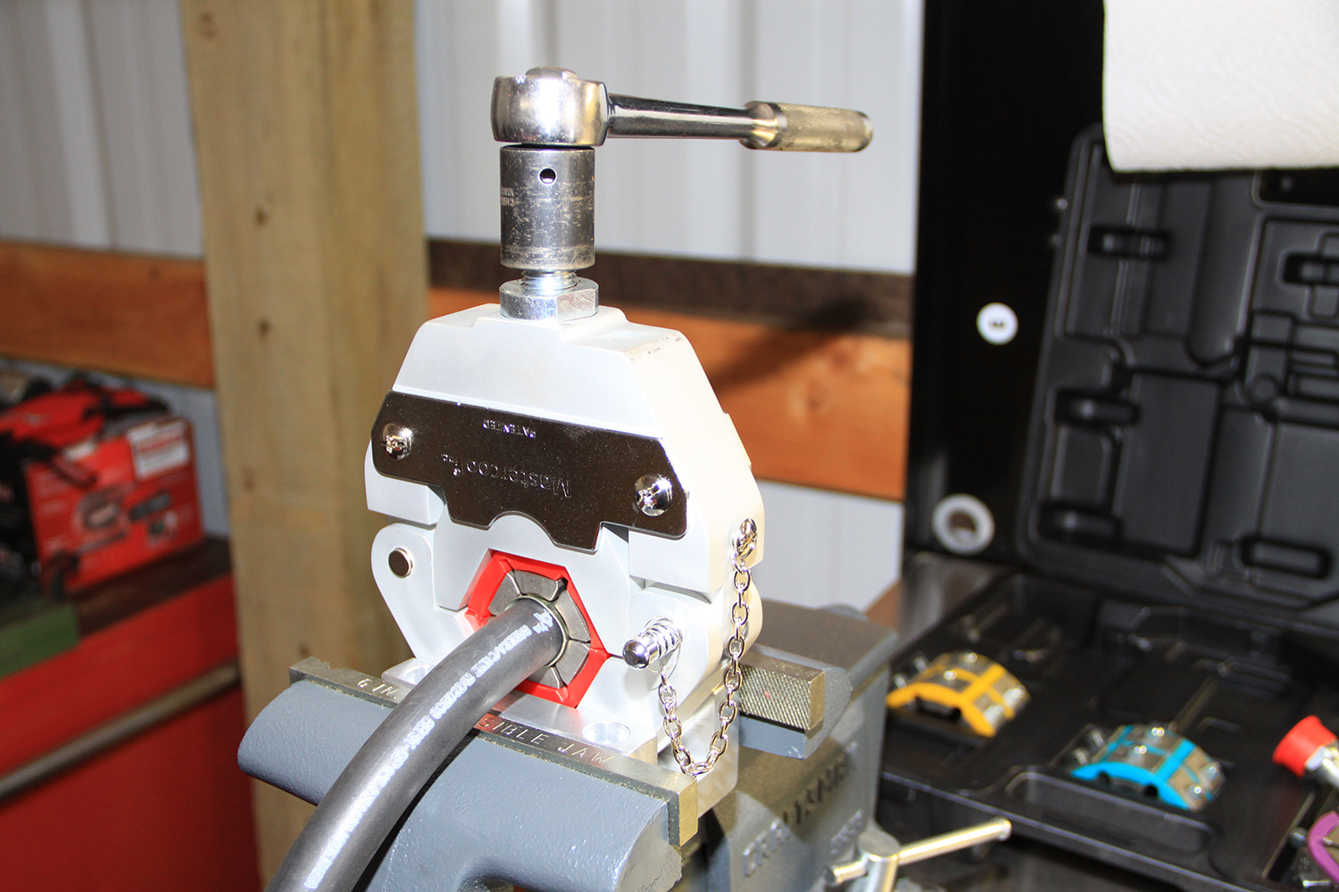 22 A hydraulic crimping tool securing an AC hose fitting in a vise for proper installation