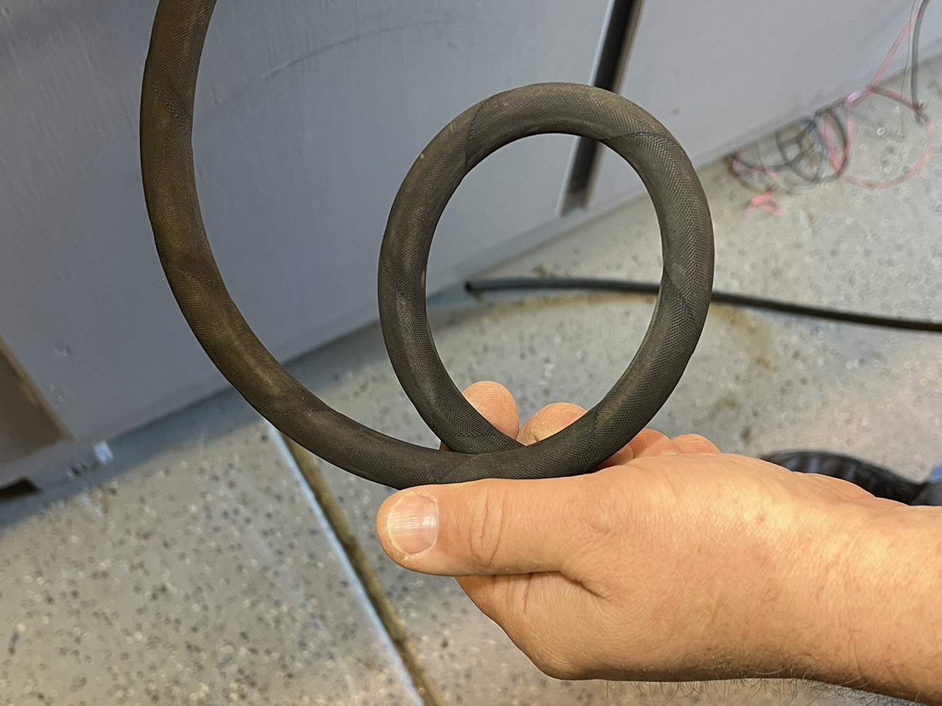 26 Hand holding a coiled rubber AC hose demonstrating flexibility and durability