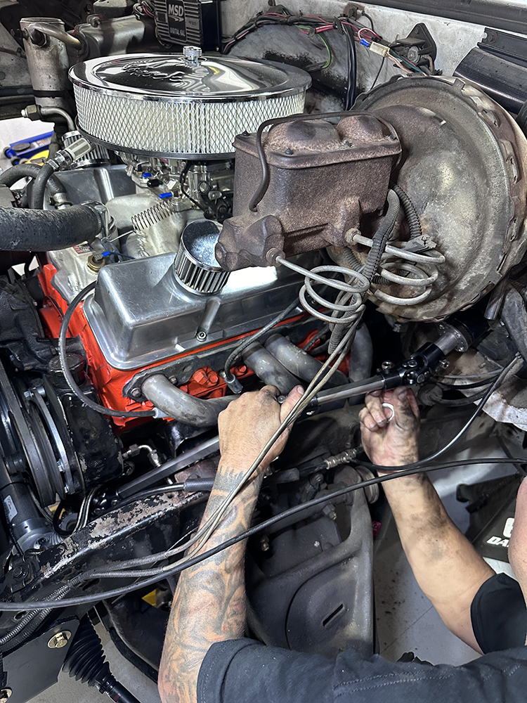 30 Technician installing the new steering shaft under the hood of the Chevy truck