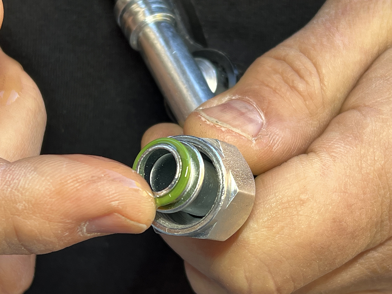 31 hand applying lubricant to a green O ring on an AC hose fitting for a proper seal