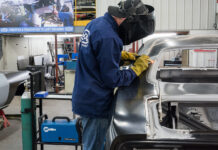 00 technician welding the new quarter panel onto the car using a Miller welder for precision attachment