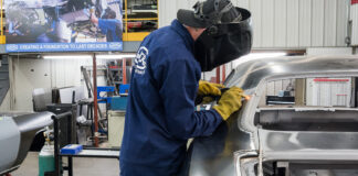 00 technician welding the new quarter panel onto the car using a Miller welder for precision attachment