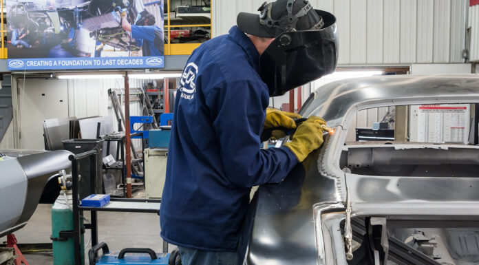 00 technician welding the new quarter panel onto the car using a Miller welder for precision attachment