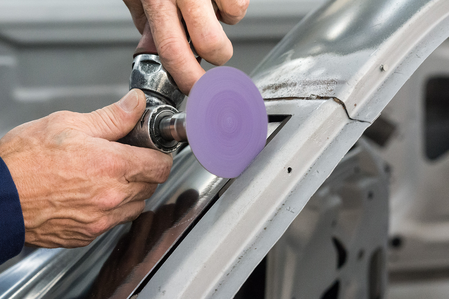 14 technician using a sanding disc to prep the panel edges before welding