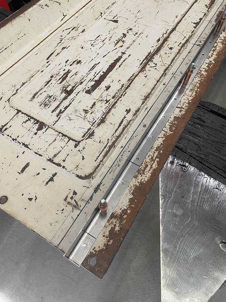 21 A weathered tailgate with a newly installed metal reinforcement strip along the lower edge