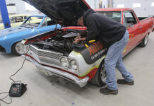 000 1965 Chevrolet El Camino with custom flames undergoing electrical repair in a classic car garage