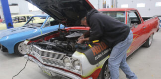 000 1965 Chevrolet El Camino with custom flames undergoing electrical repair in a classic car garage