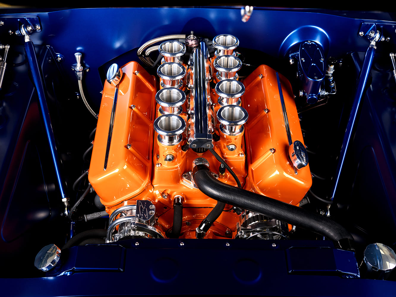 006 1966 Chevrolet Nova engine bay with a high performance orange big block V8 and velocity stacks