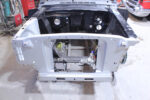 01 Ford Mustang core support with bare engine bay and fresh primer showcasing steering rack and chassis rails