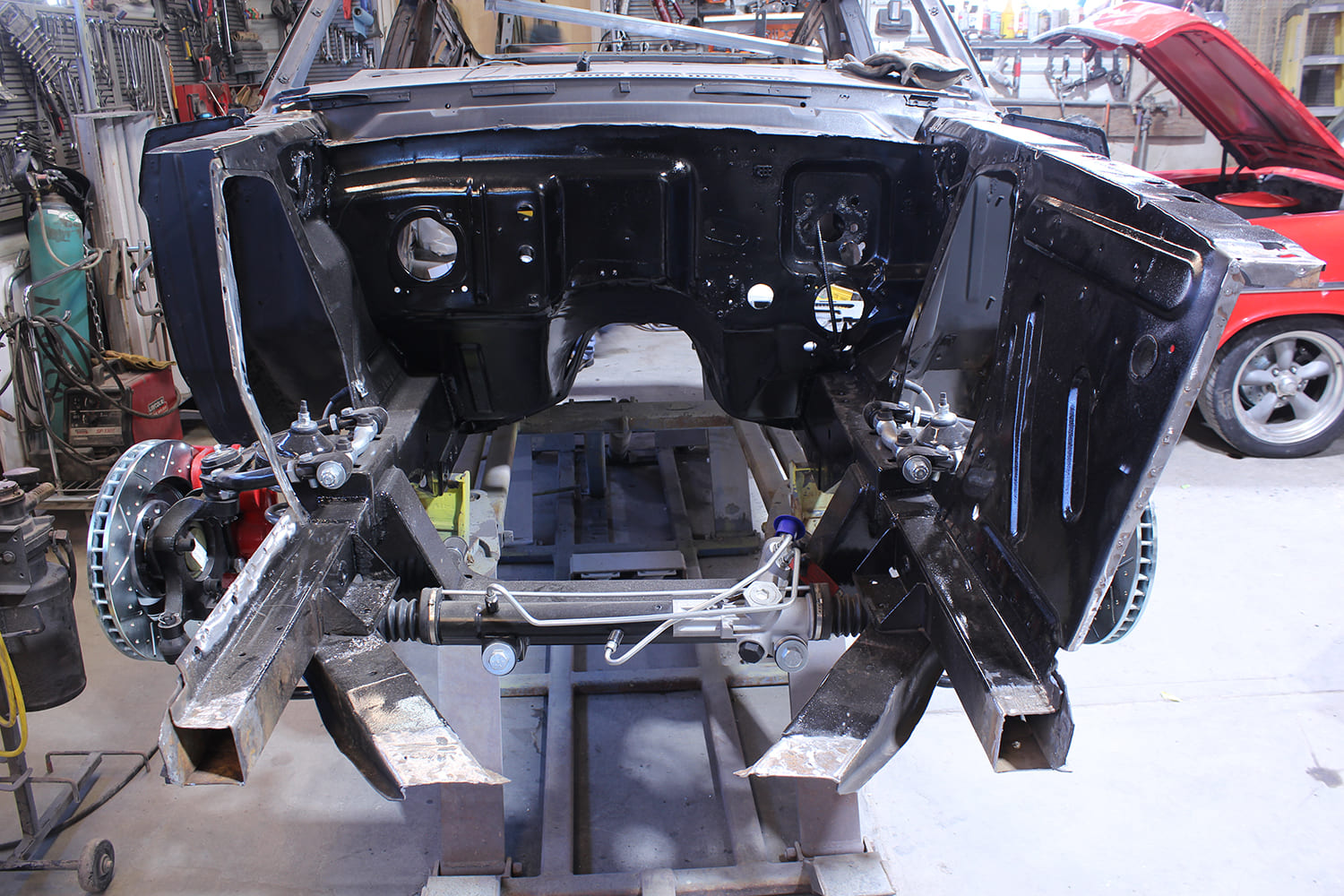 12 Mustang front clip prepped with mockup chassis legs and black firewall paint ahead of apron installation