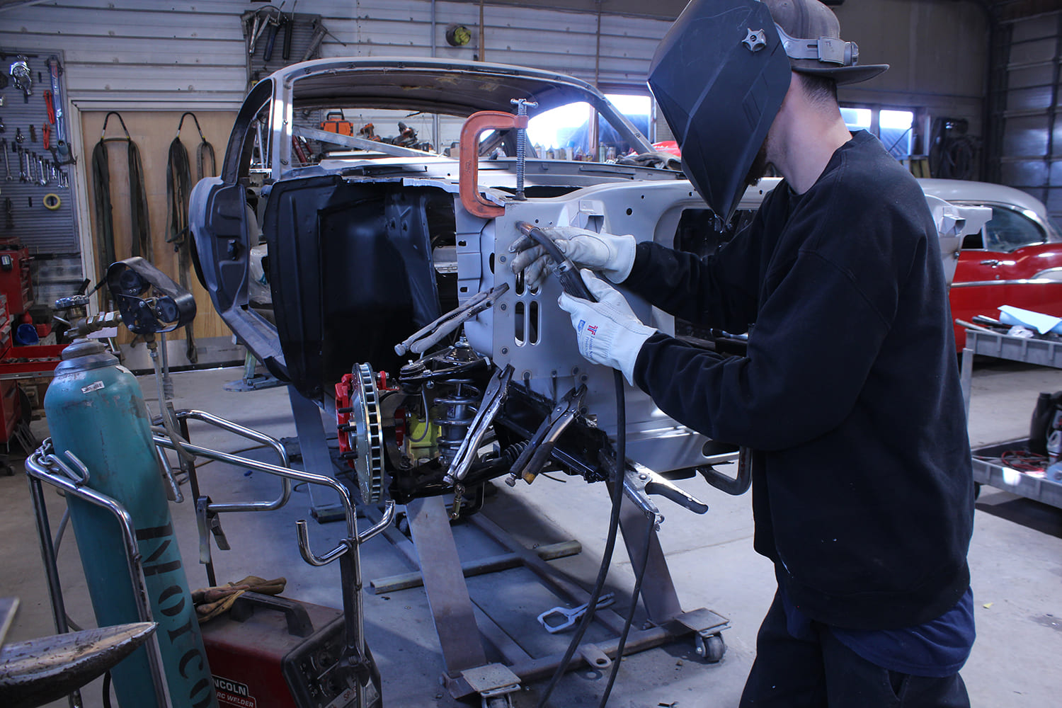 20 Technician welding radiator core support on classic Mustang with clamps and Lincoln Electric setup