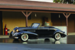 01 1939 Cadillac Convertible black with whitewalls and chrome trim parked under vintage gas station awning