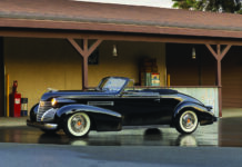 01 1939 Cadillac Convertible black with whitewalls and chrome trim parked under vintage gas station awning