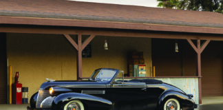 01 1939 Cadillac Convertible black with whitewalls and chrome trim parked under vintage gas station awning