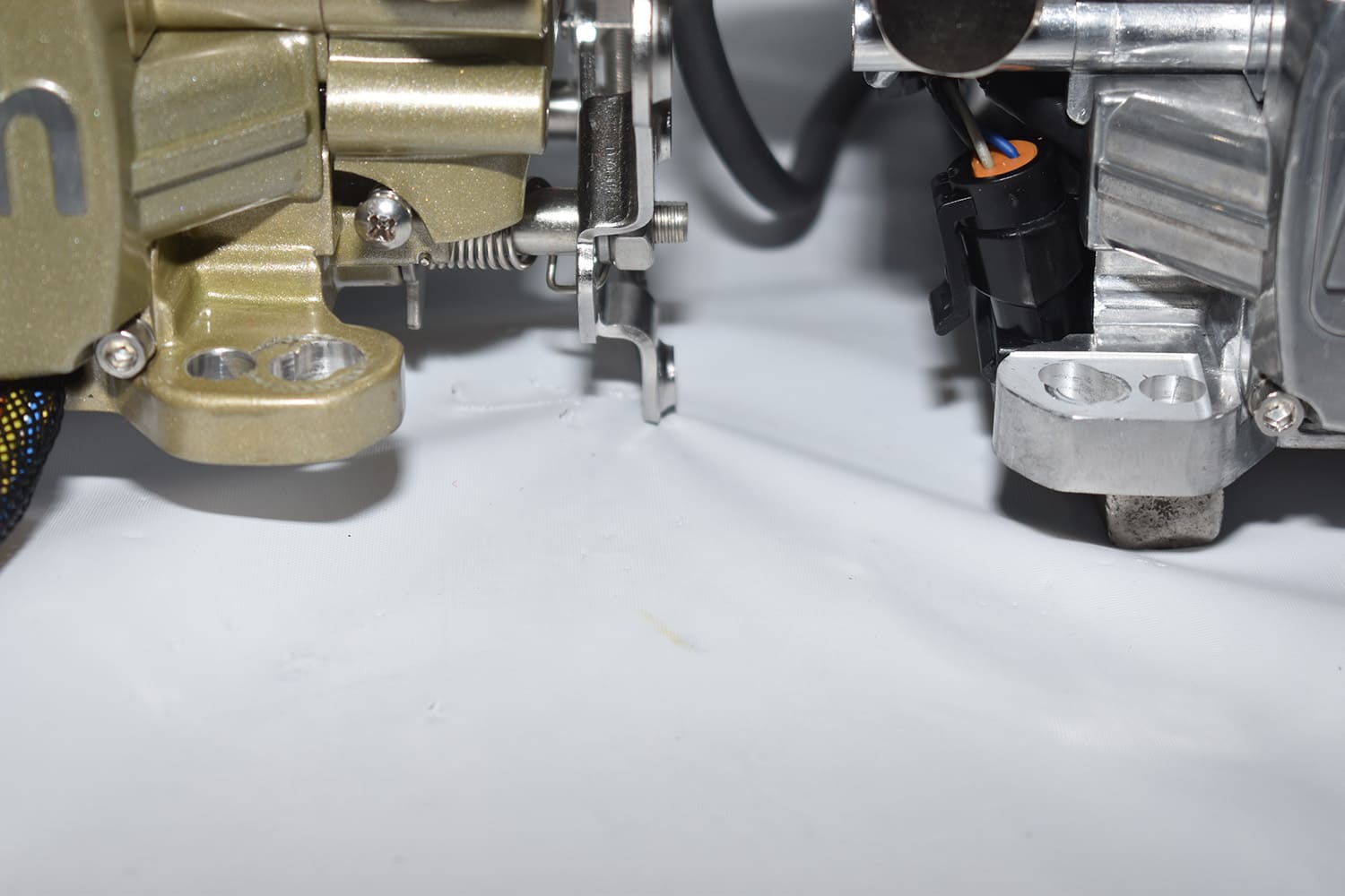 05 Mounting base comparison of gold and aluminum FiTech throttle bodies with bolt hole spacing