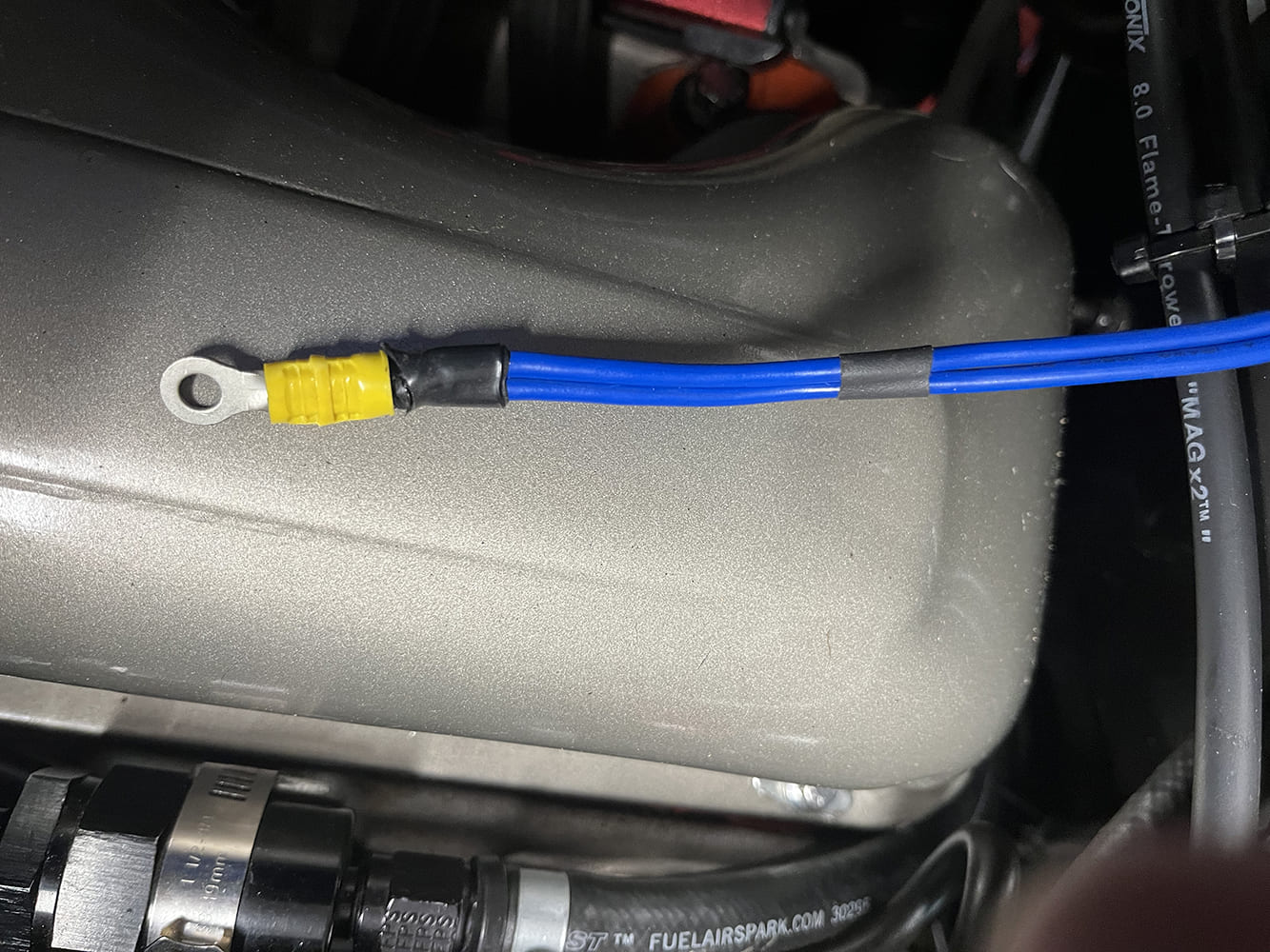 16 Ground terminal with blue wire routed along valve cover for chassis connection