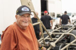 21 George Poteet wearing Bonneville 200 MPH Club hat beside land speed race car chassis at dry lakes event