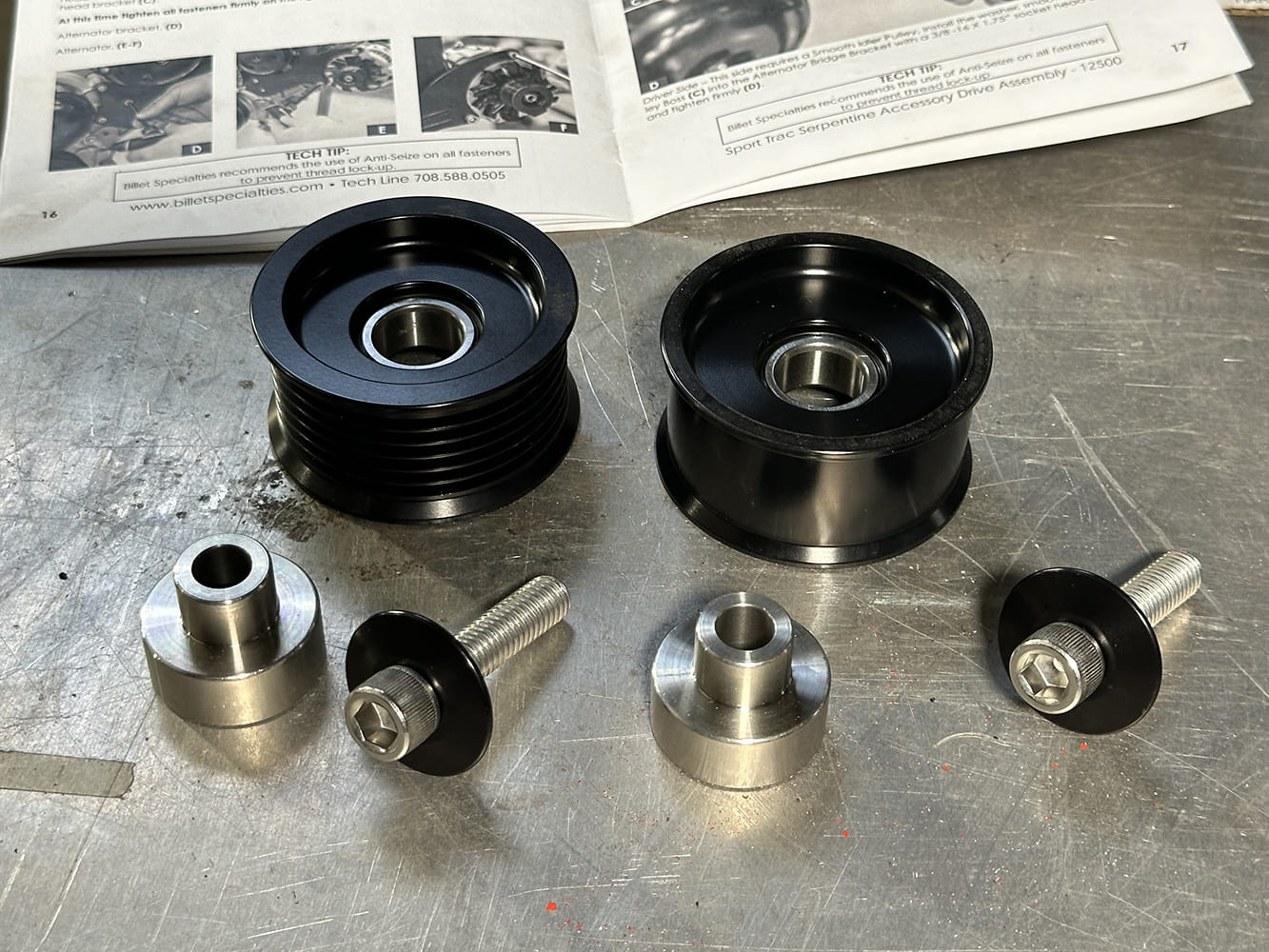 27 Smooth and grooved idler pulleys with spacers laid out next to Billet instructions