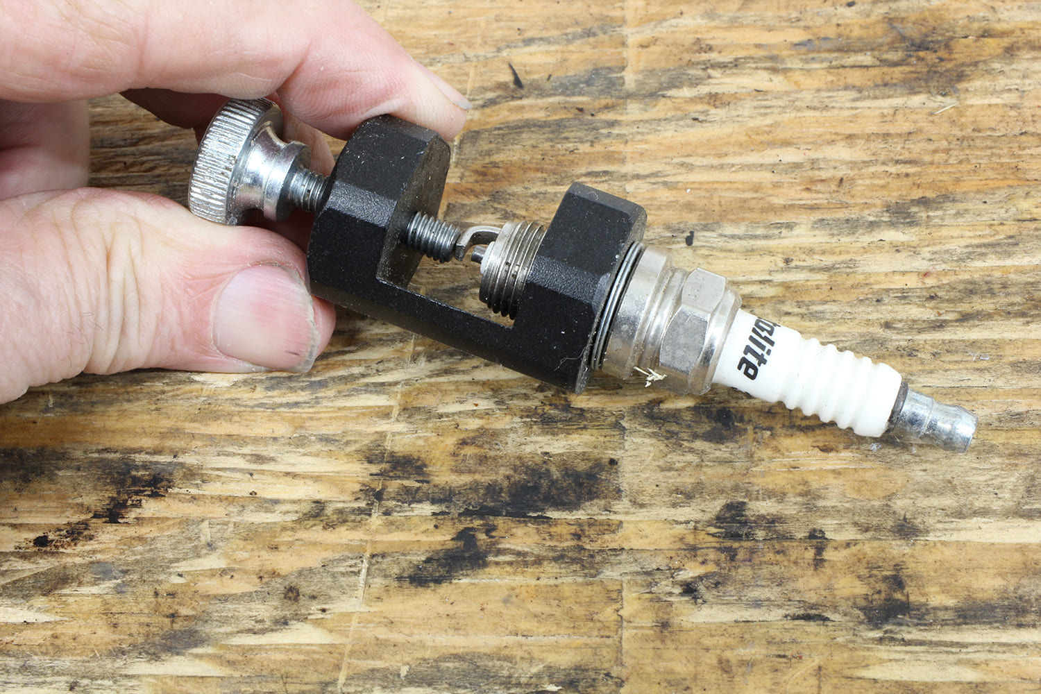 008 Manual gapping tool in use on a spark plug to adjust electrode spacing precisely