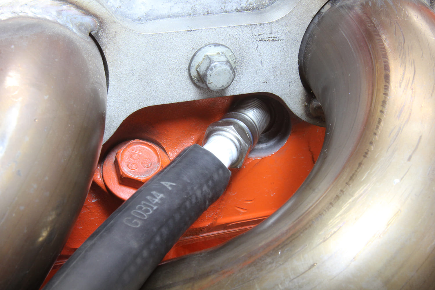 009 Spark plug installed in a tight fit cylinder head surrounded by custom fabricated exhaust headers