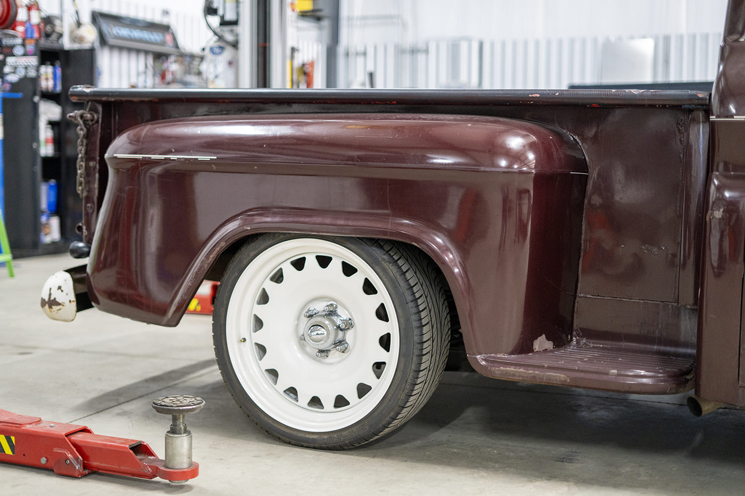 01 Rear driver side view of maroon C10 showing custom white steel wheels and worn patina finish