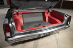 024 1966 Chevy Nova trunk lined in red and grey upholstery with fuel cell access port