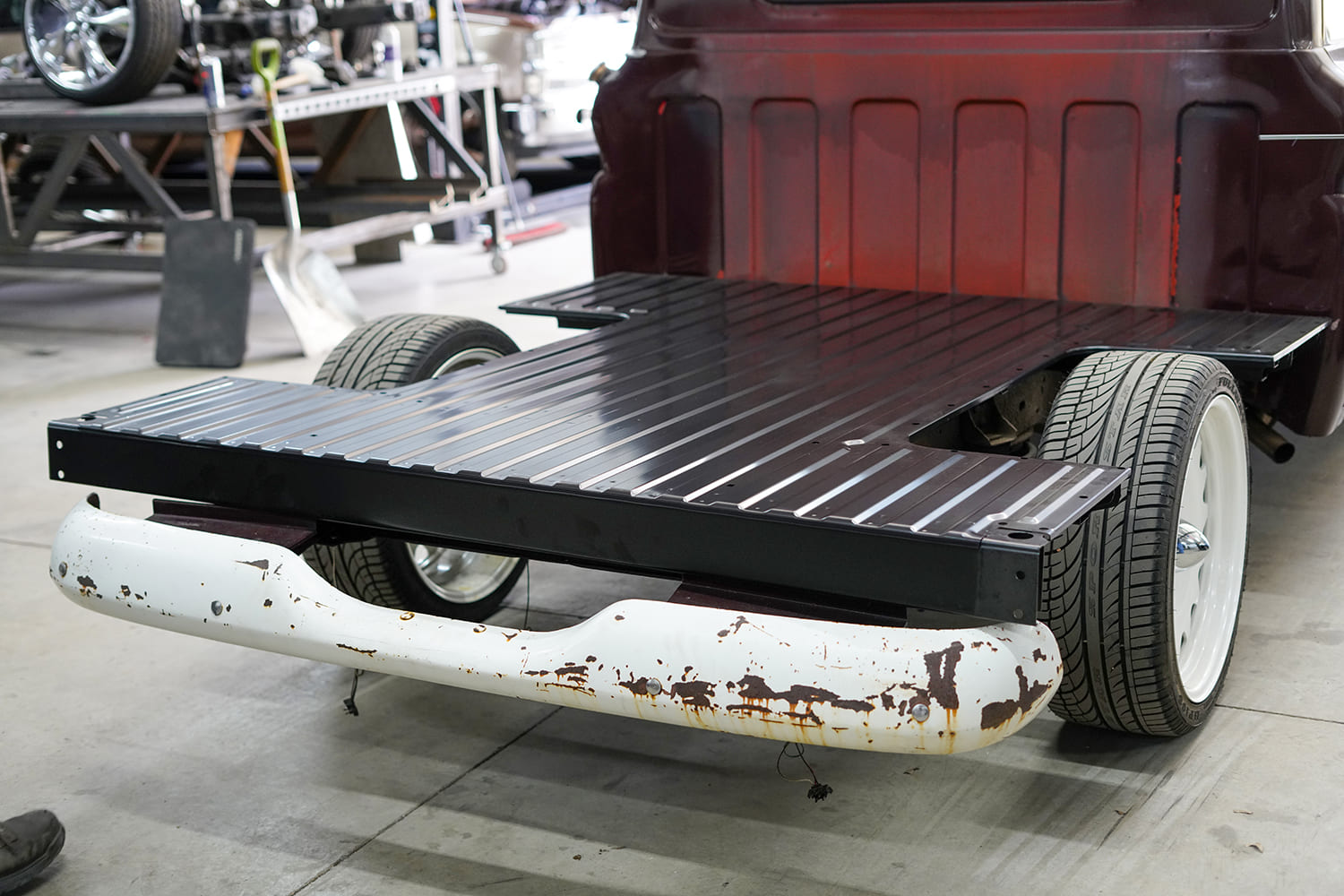 08 Fabricator drills mounting holes into new black steel bed floor laid over the C10 frame