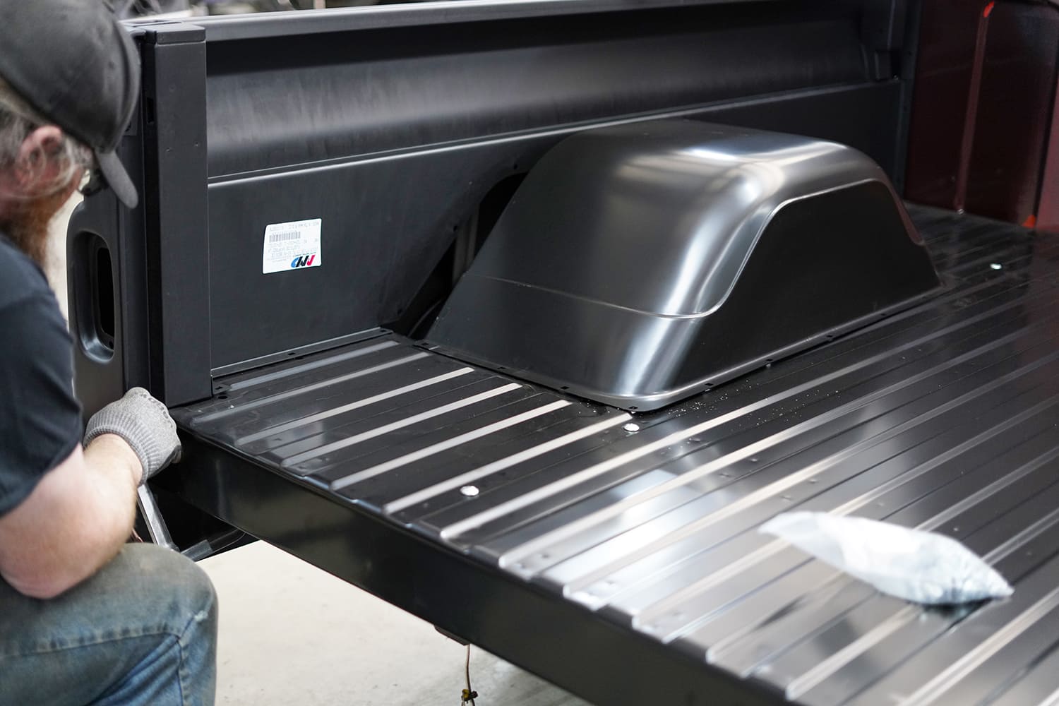 12 A CJ Classic Trucks steel bed panel is being installed with fasteners into the maroon C10 bed