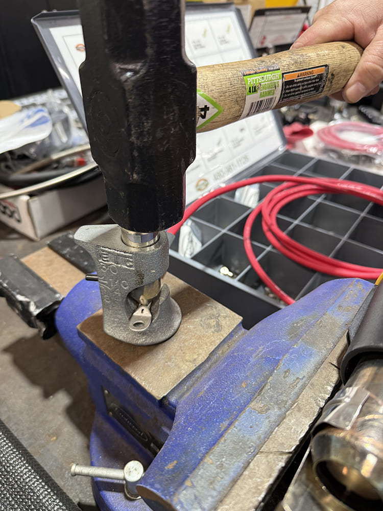 15 Hydraulic crimp tool compressing heavy gauge terminal with hammer on vise