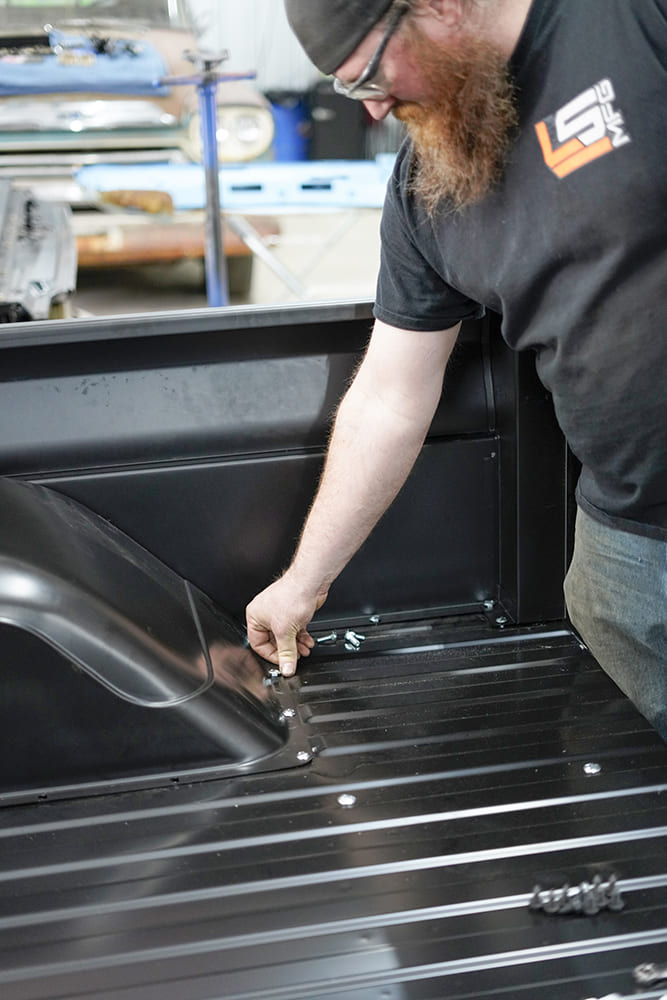 21 Installer hand tightens bed bolts securing the CJ Classic wheel tub to the steel bed floor panel