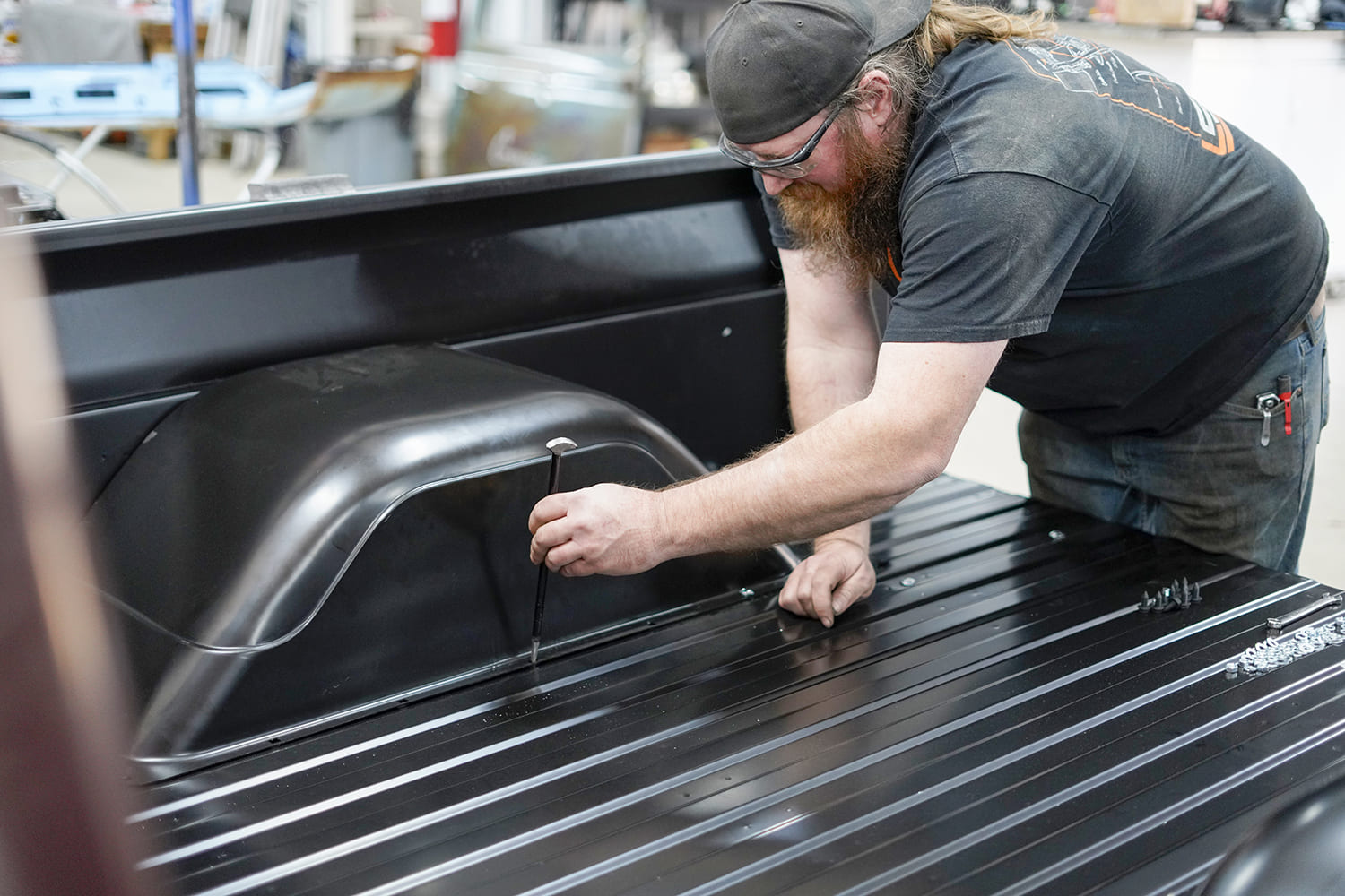 23 Technician aligns and punches fastener holes on the wheel tub to complete the bolt in bed kit