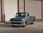 01 1957 Ford F 100 custom build in slate gray with chrome trim parked at industrial building