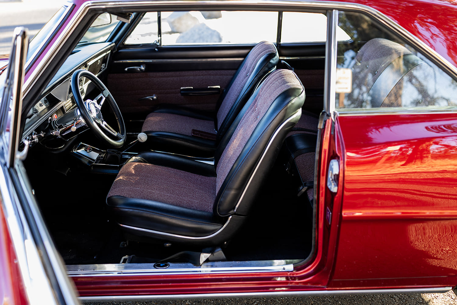 010 1966 Chevy Nova interior has black and maroon bucket seats floor shifter and custom steering wheel