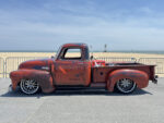 03 1950 Chevrolet 3100 patina truck with lowered stance and custom multi spoke wheels at the beach