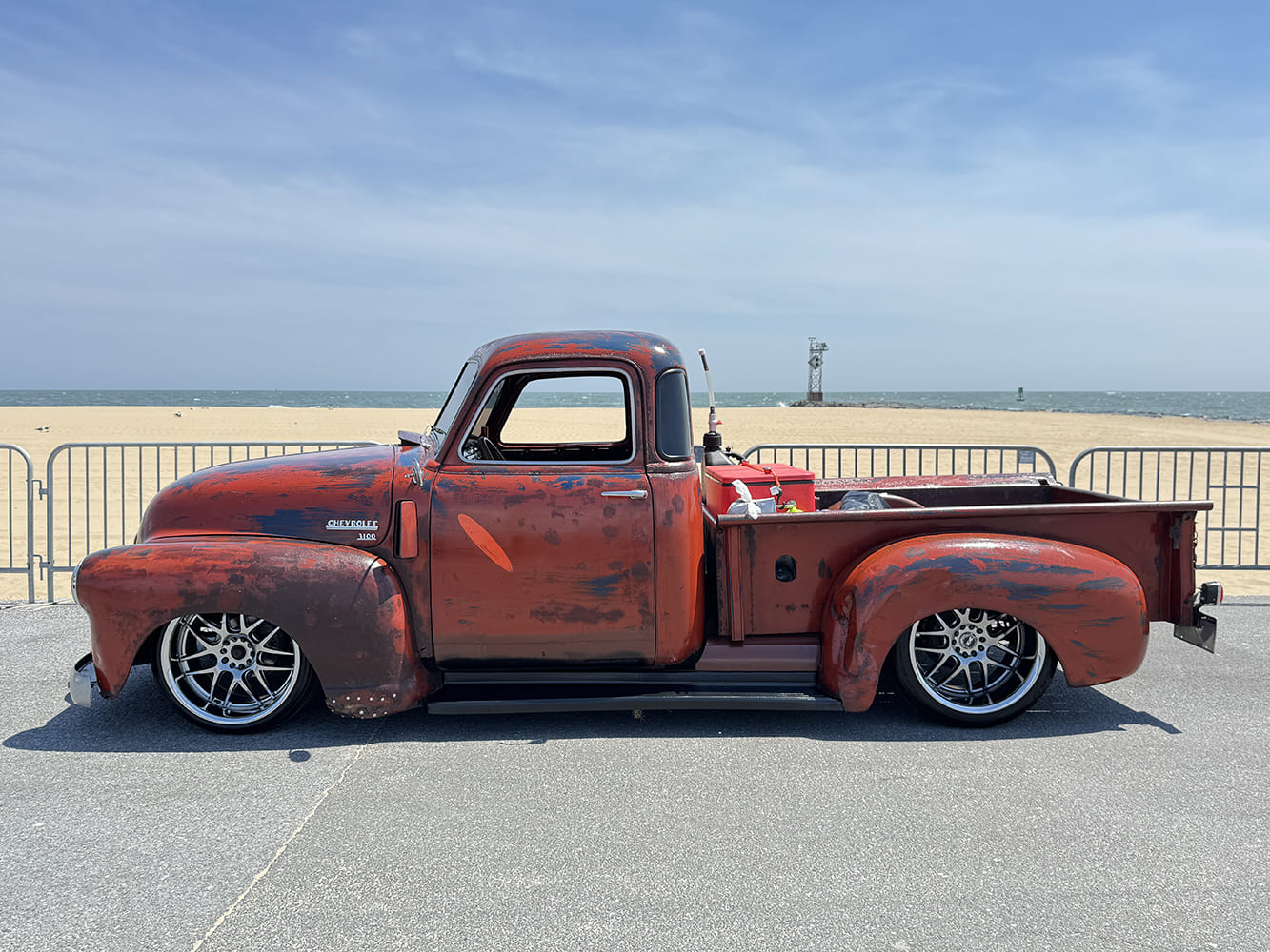 03 1950 Chevrolet 3100 patina truck with lowered stance and custom multi spoke wheels at the beach