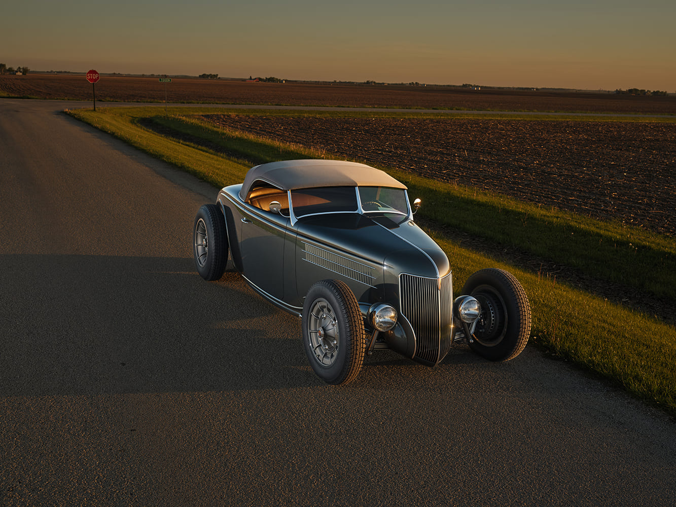 08 1936 Ford highboy parked at country crossroads with golden interior reflecting in windshield