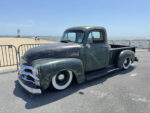 20 1954 Chevrolet 3100 in aged green patina with whitewalls and lowered stance by the beach