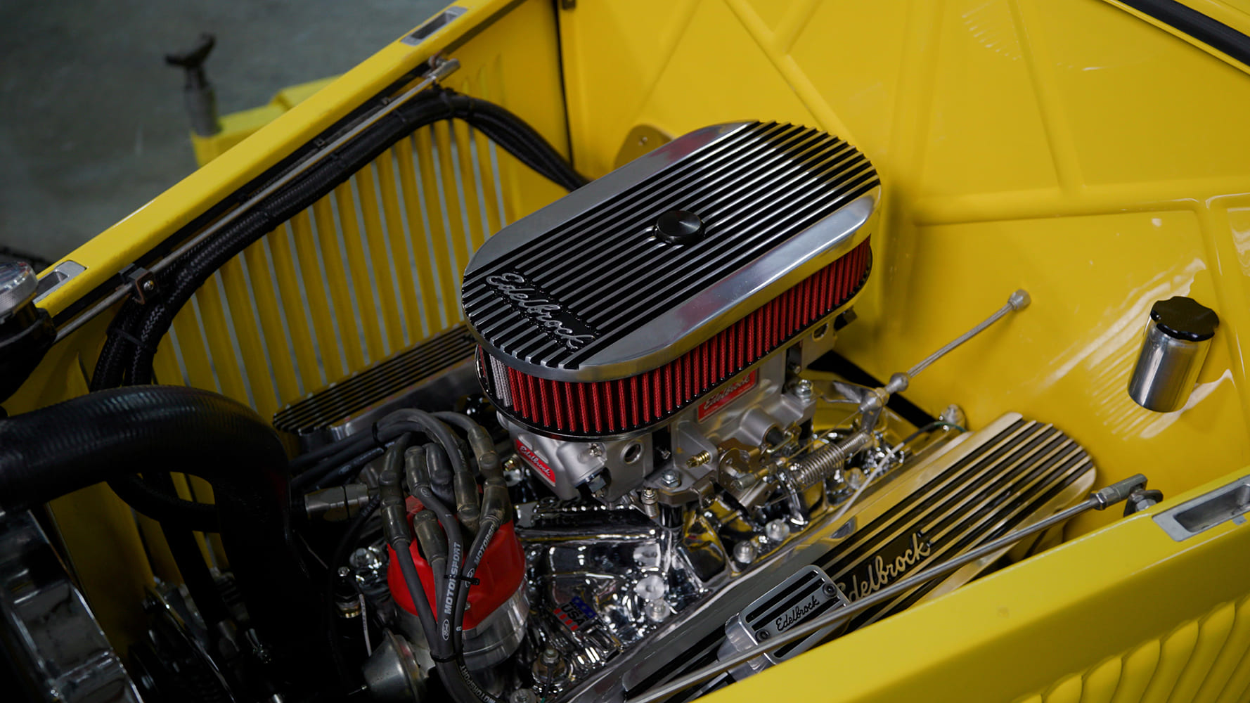22 Edelbrock VRS 4150 installed with matching air cleaner and red filter in yellow hot rod