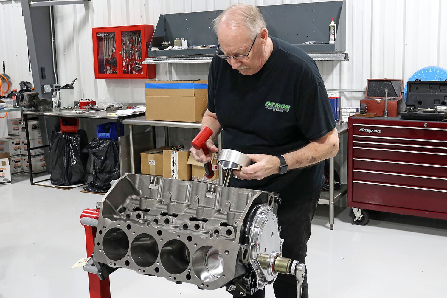 006 Technician installing forged piston into engine block using ring compressor