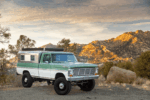25 1969 Ford F 250 Delmo 4x4 build with pop top camper parked in front of mountain sunset