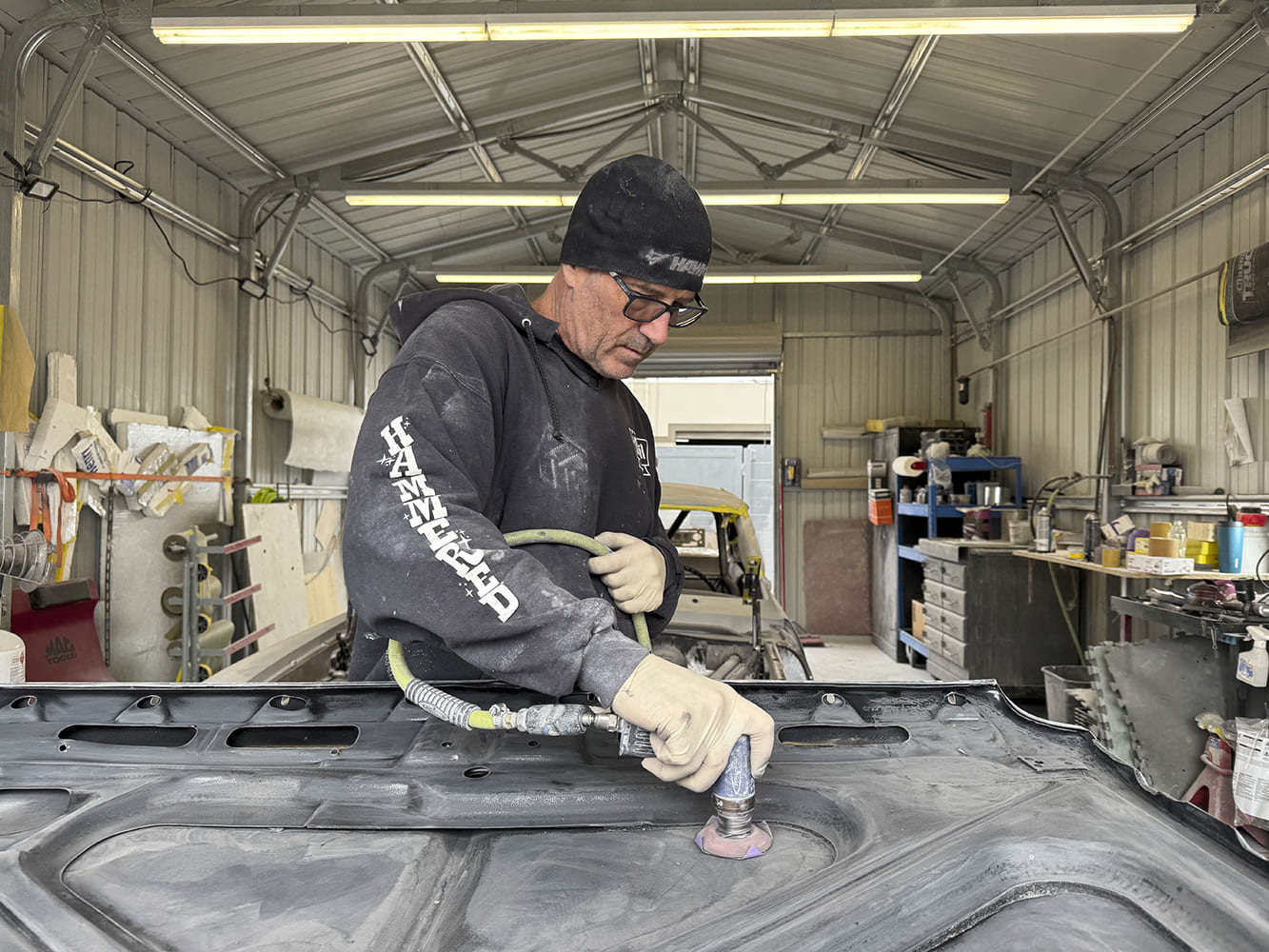 010 Technician sanding underside of 1963 Chevy Nova hood with DA sander