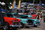 24 Red and turquoise 1955 Chevrolets parked side by side vendor tents car show atmosphere