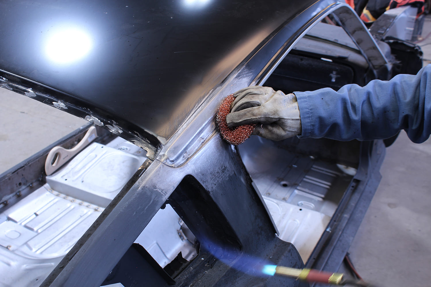 29 Technician tack welds roof perimeter finalizing panel replacement on '65 Mustang Fastback