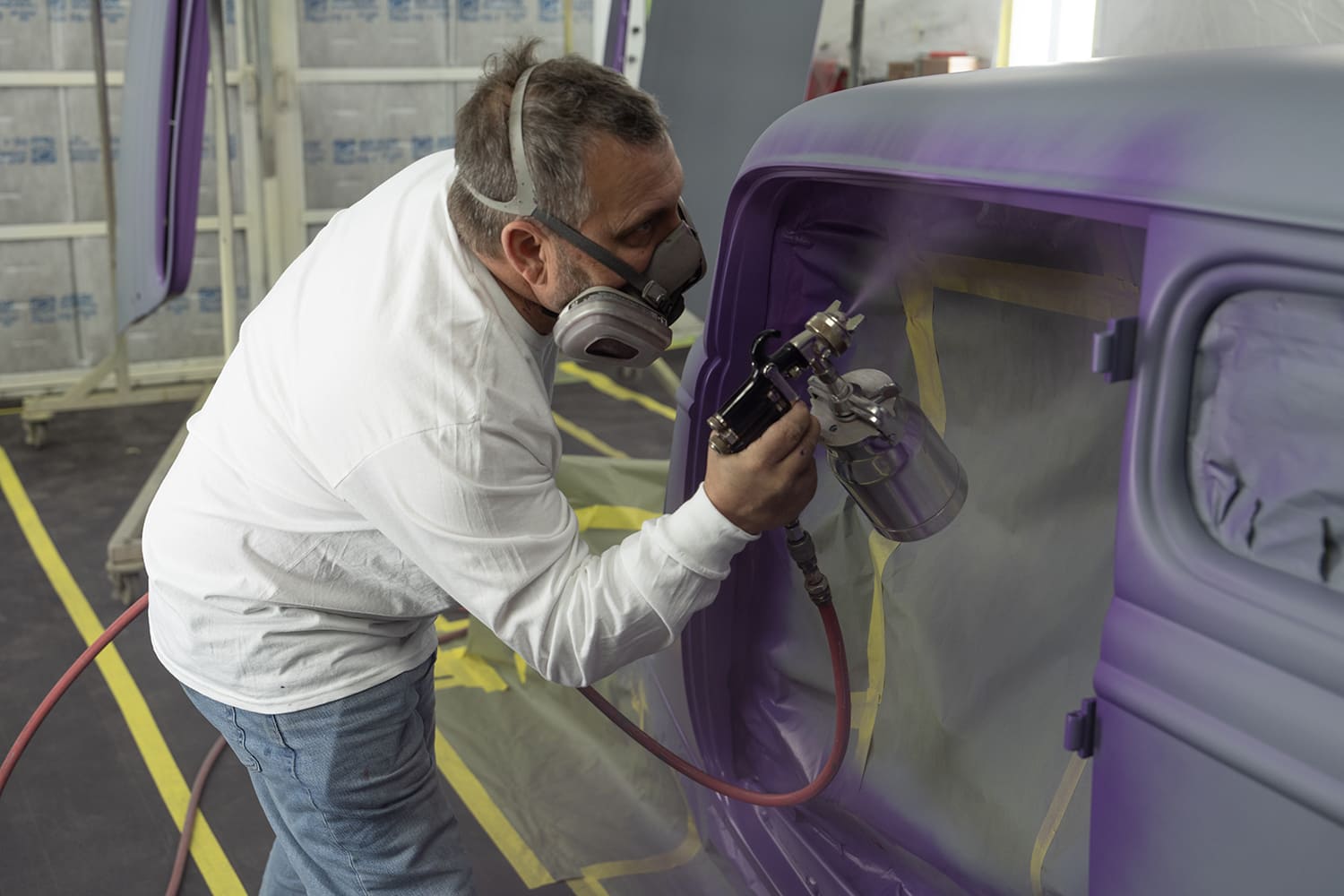 06 Technician applying metallic purple paint to 1930s Ford coupe in booth