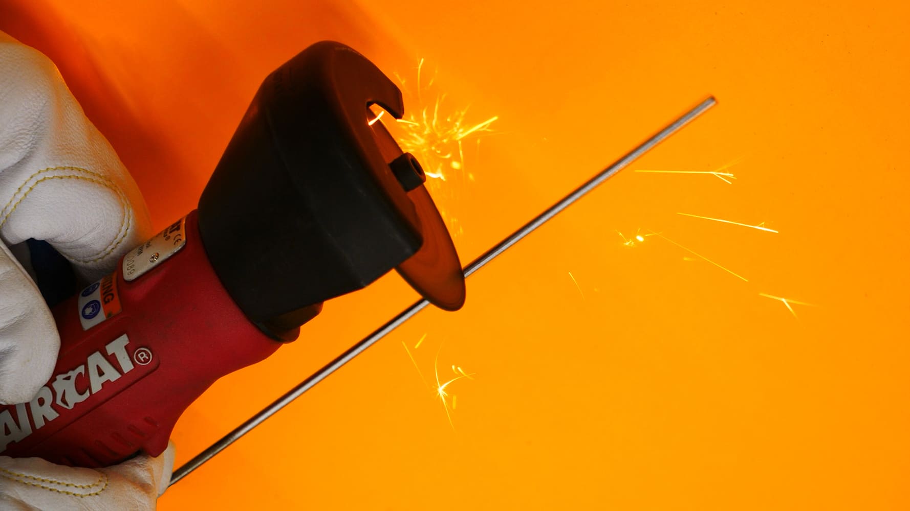 07 AIRCAT red rotary tool cutting tungsten gloved hand bright sparks orange backdrop