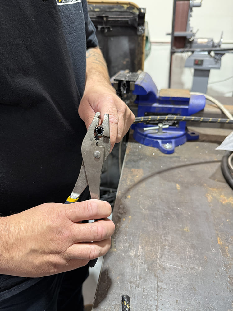 11 Inspecting braided hose cut with pliers to verify clean straight end for fitting