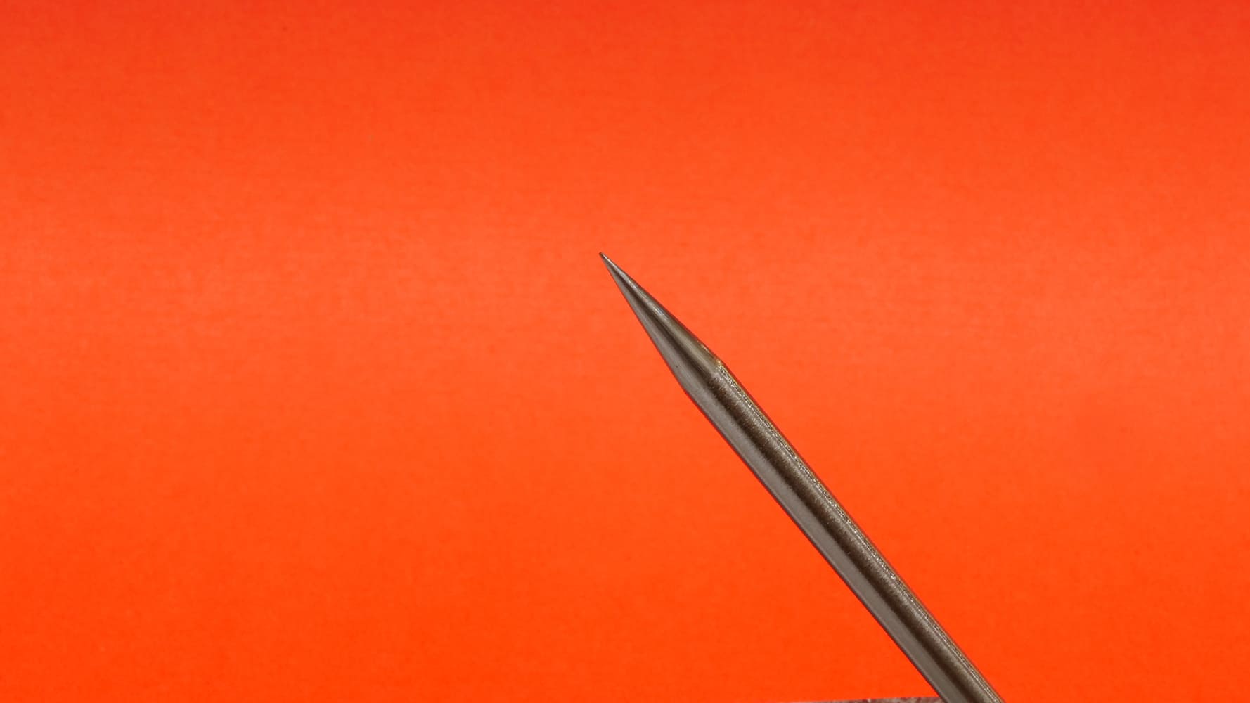 15 Single TIG tungsten electrode long taper tip close up orange background