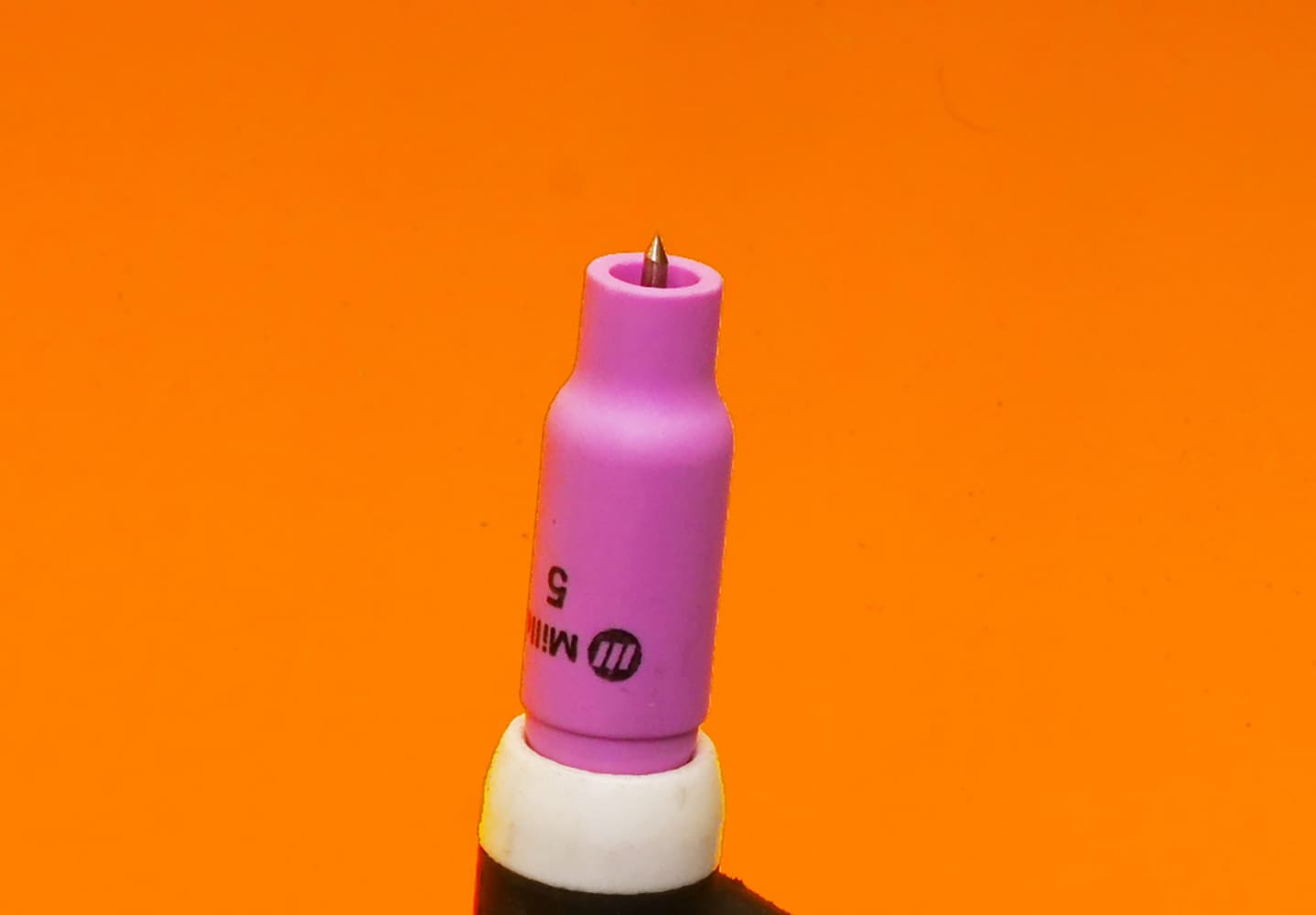 18 TIG torch close up pink MILLER #5 cup tungsten tip white band below cup orange background