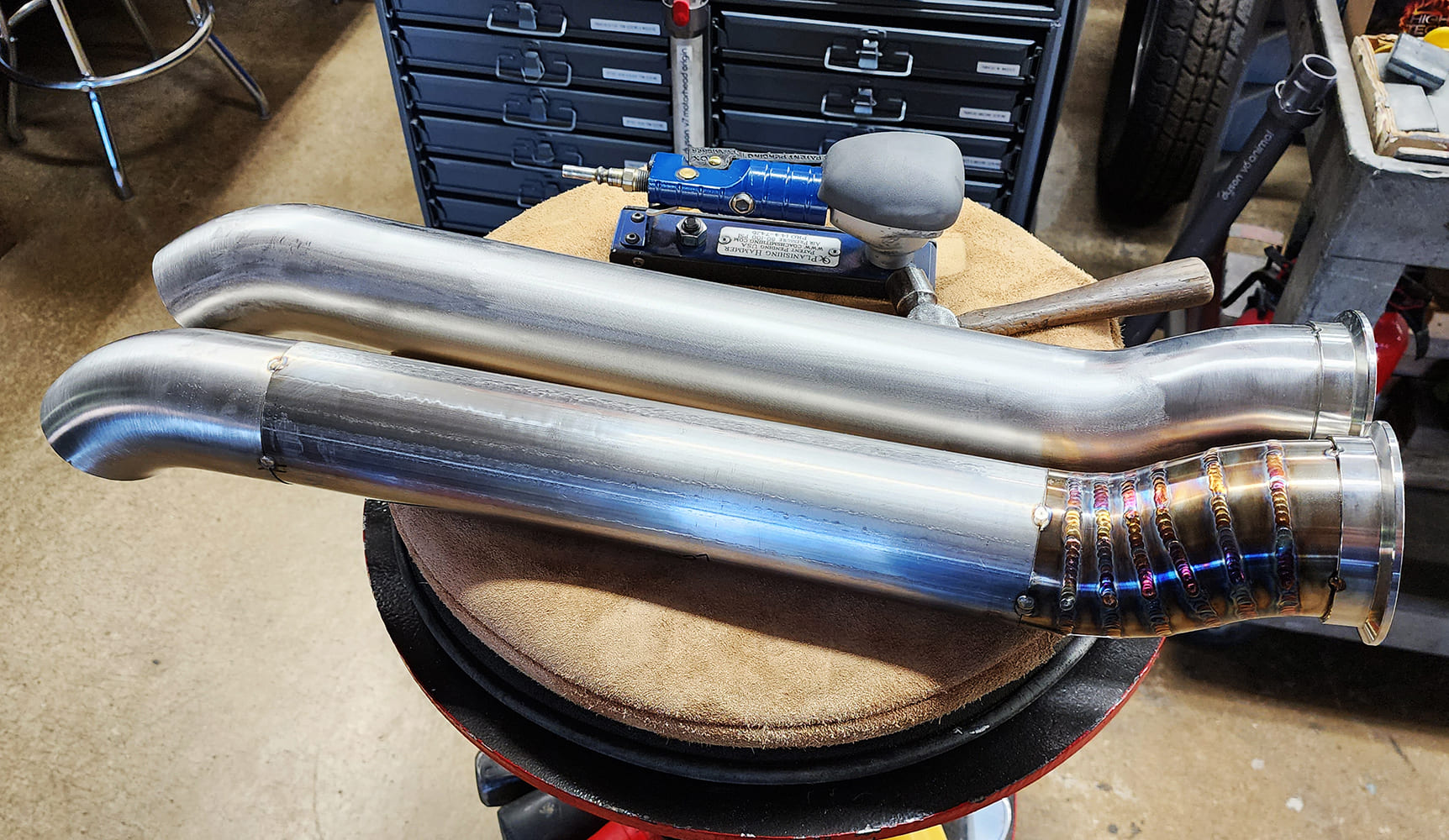 19 Dual stainless exhaust pipes V band clamps multi color weld beads workbench assembly