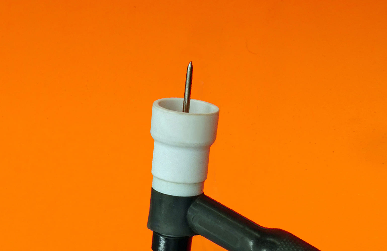20 TIG torch white ceramic cup centered tungsten partial handle in frame orange background
